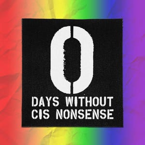 May include: A square black fabric patch featuring a large white stencil-style number zero at the top. Below the number, the white text reads "DAYS WITHOUT CIS NONSENSE" in a matching stencil font. The patch has a textured, woven appearance.