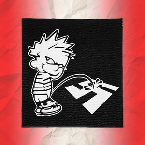 May include: A square black fabric patch featuring a white graphic illustration of a cartoon character with spiky hair and a striped shirt urinating on a white swastika symbol. The design is rendered in high-contrast white lines on a black background.