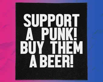 May include: A square black fabric patch featuring the white text SUPPORT A PUNK! BUY THEM A BEER! in a bold, sans-serif font. The patch has a visible woven texture and clean, straight edges, presenting a high-contrast design on a dark background.