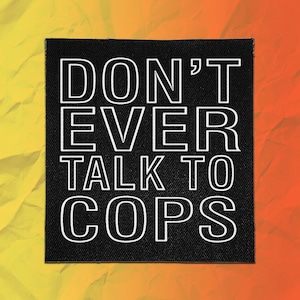 May include: A square black fabric patch featuring the white text DON'T EVER TALK TO COPS in a bold, sans-serif font. The patch has a visible woven texture and clean, straight edges, presenting a high-contrast design against the dark background.