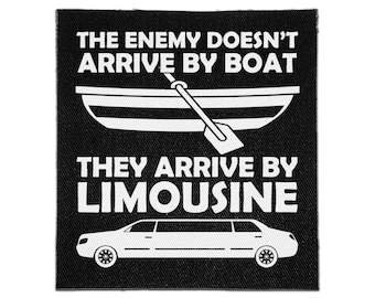 May include: A square black fabric patch featuring white screen-printed graphics and text. The design includes a rowboat with an oar and a limousine, accompanied by the text: THE ENEMY DOESN'T ARRIVE BY BOAT THEY ARRIVE BY LIMOUSINE.
