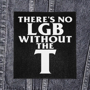 May include: Black square patch with white text that reads "THERE'S NO LGB WITHOUT THE T". The patch is on a denim jacket.