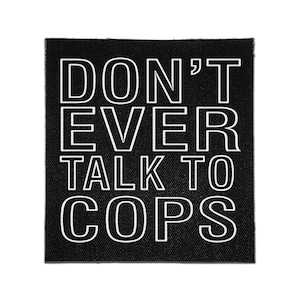 Op de afbeelding: Een vierkante zwarte stoffen patch met de witte tekst DON'T EVER TALK TO COPS in een vetgedrukt, schreefloos lettertype. De patch heeft een zichtbare geweven textuur en strakke randen, wat zorgt voor een contrastrijk ontwerp met duidelijke letters.