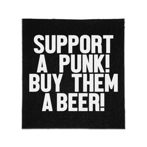 May include: A square black fabric patch featuring the white text SUPPORT A PUNK! BUY THEM A BEER! in a bold, sans-serif font. The patch has a visible woven texture and clean, straight edges, presenting a high-contrast design on a dark background.