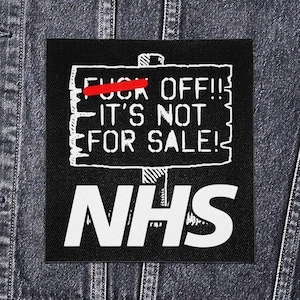 May include: Black square patch with white text: "FUCK OFF!! IT'S NOT FOR SALE!" with a red line through "FUCK". The letters "NHS" are at the bottom. The patch is on a denim jacket.
