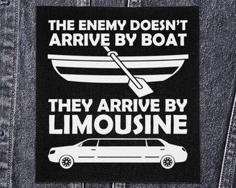 May include: Black square patch with white text and graphics. The text reads "THE ENEMY DOESN'T ARRIVE BY BOAT THEY ARRIVE BY LIMOUSINE." A boat and paddle are above the text, and a limousine is below.