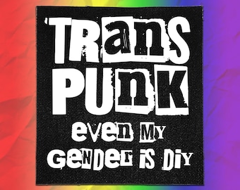 May include: A square black fabric patch featuring white text that reads TRANS PUNK in a bold, distressed font, followed by the text even MY GENDER is DIY in a smaller, mixed-case font. The patch has a visible woven texture throughout the surface.