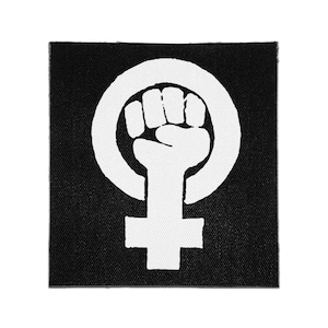 May include: A square fabric patch with a black background and a white screen-printed graphic. The design features a raised fist centered within a circular ring, forming a symbol that extends downward into a cross shape at the bottom of the patch.