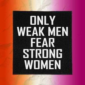 Könnte beinhalten: Ein quadratischer schwarzer Stoffaufnäher mit dem weißen Text ONLY WEAK MEN FEAR STRONG WOMEN in einer fetten, serifenlosen Schrift. Der Aufnäher hat eine sichtbare Webstruktur und saubere, gerade Kanten für ein klares Design.