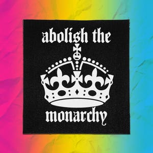 May include: A square black fabric patch featuring a white graphic of a crown in the center. The text "abolish the" is printed in white above the crown, and the word "monarchy" is printed in white below the crown in a gothic font style.