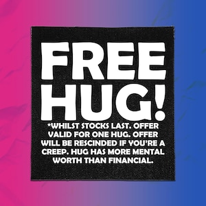 May include: A square black fabric patch featuring the white text FREE HUG! followed by the smaller text *WHILST STOCKS LAST. OFFER VALID FOR ONE HUG. OFFER WILL BE RESCINDED IF YOU'RE A CREEP. HUG HAS MORE MENTAL WORTH THAN FINANCIAL.