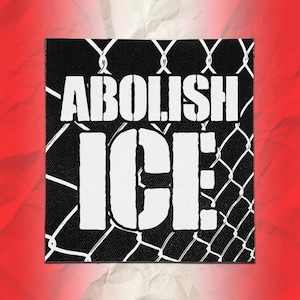 Könnte beinhalten: Ein quadratischer Stoffaufnäher mit schwarzem Hintergrund und einem weißen Maschendrahtzaunmuster. Der Text ABOLISH ICE ist in großen, fetten, weißen Großbuchstaben in der Mitte des Aufnähers aufgedruckt und überlagert das Zaunmotiv.
