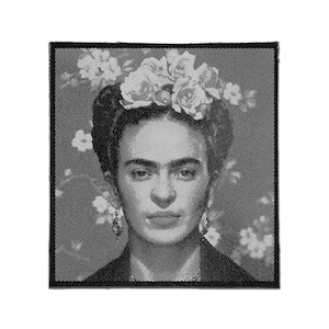 May include: A square fabric patch featuring a black and white halftone portrait of Frida Kahlo. The image displays her iconic floral headpiece and dark hair, rendered in a dotted pattern with a solid black border framing the entire square design.