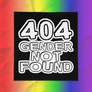 May include: A square black fabric patch featuring white embroidered text that reads 404 GENDER NOT FOUND. The lettering is bold and outlined in a clean, sans-serif style, centred on the dark background to create a high-contrast visual effect.