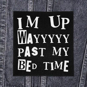 May include: Black square patch with white text that reads "I'M UP WAYYYYY PAST MY BED TIME." The patch is sewn onto a dark denim jacket. The text is in a bold, sans-serif font.