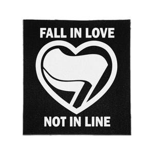 May include: A square black fabric patch featuring white text that reads FALL IN LOVE at the top and NOT IN LINE at the bottom. In the center, a white heart outline contains a stylized white flag graphic with a diagonal orientation.