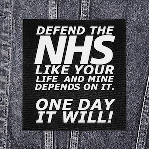 May include: Black square patch with white text: "DEFEND THE NHS LIKE YOUR LIFE AND MINE DEPENDS ON IT. ONE DAY IT WILL!" The patch is attached to a denim jacket.