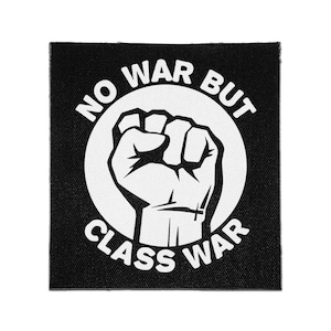 Puede incluir: Un parche cuadrado de tela negra con un gráfico circular blanco de un puño levantado en el centro. El texto NO WAR BUT CLASS WAR está impreso en letras mayúsculas blancas, arqueándose sobre y curvándose bajo la ilustración del puño.