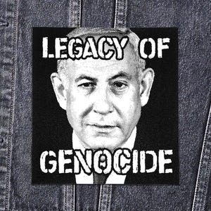 Peut inclure: Écusson noir et blanc avec un portrait d'homme et l'inscription "LEGACY OF GENOCIDE" en lettres blanches et grasses. L'écusson carré est fixé sur une veste en jean.