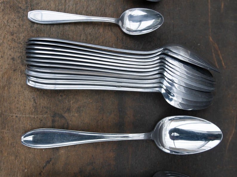 May include: A stack of silver spoons, with one spoon on top and another spoon on the bottom. The spoons are arranged in a row, with the handles pointing to the right.