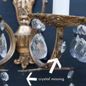 K&ouml;nnte beinhalten: Goldene Wandleuchte aus Metall mit Kristalltropfen. Ein Kristall fehlt an der Leuchte.