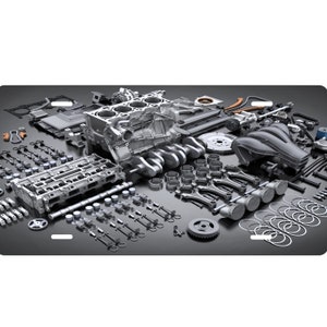 May include: A disassembled car engine with all of its parts laid out on a gray surface. The engine block, pistons, connecting rods, crankshaft, camshafts, valves, and other components are visible.