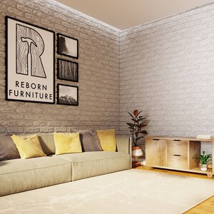 May include: A light beige sofa with yellow and gray throw pillows sits in front of a white brick wall. Three black framed pictures hang on the wall, one of which features the text "REBORN FURNITURE". A wooden cabinet with two drawers and an open shelf sits on the right side of the image. A potted plant sits on the shelf.