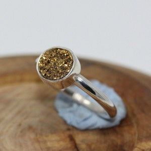 Un anillo de plata de ley en caja de regalo con una llamativa piedra preciosa Druzy dorada.