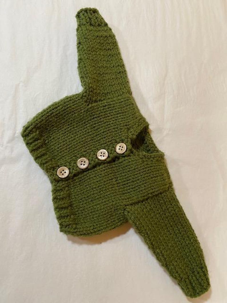 May include: A green knitted cardigan with button closures. The cardigan is made of a soft, textured yarn and has a relaxed fit.