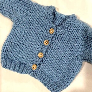 May include: A light blue knitted baby cardigan with wooden buttons.