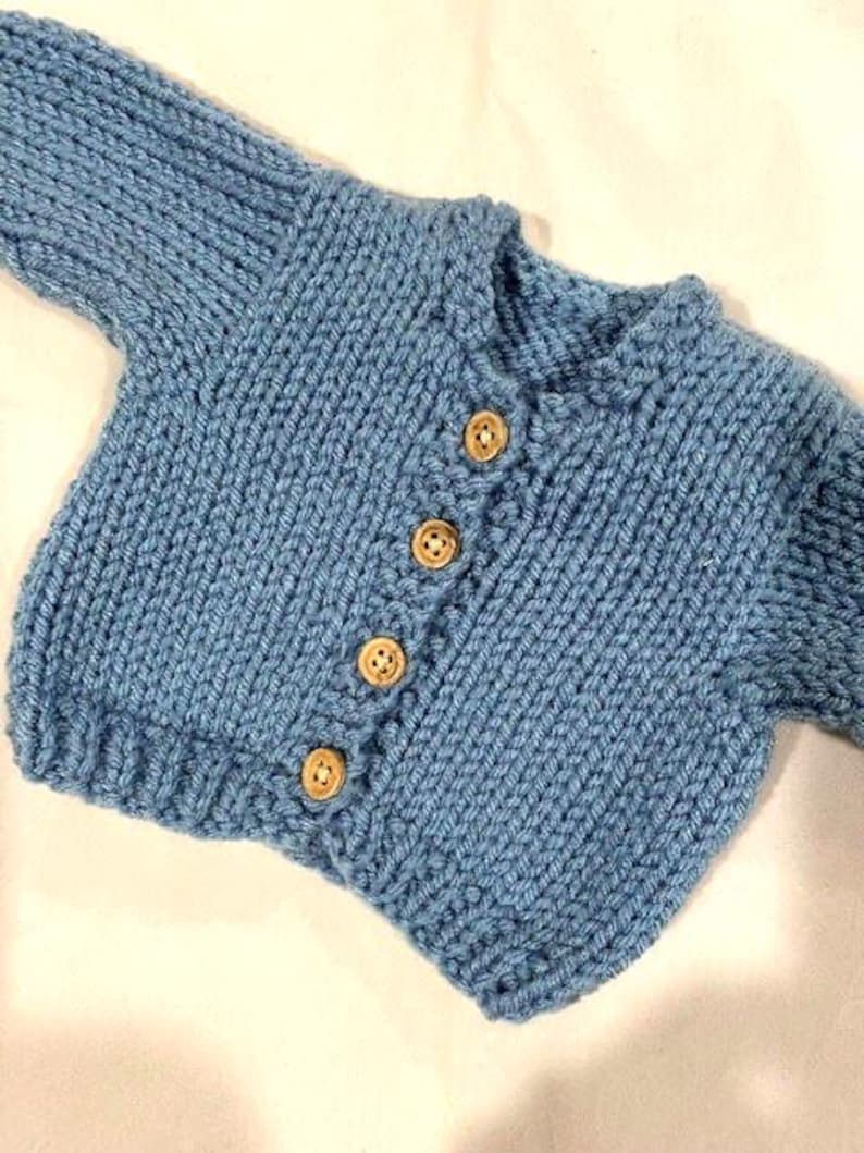 May include: A light blue knitted baby cardigan with wooden buttons.