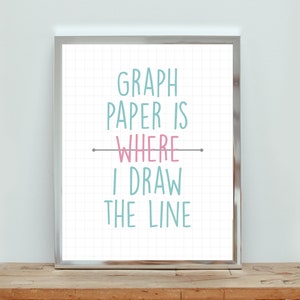 May include: A framed print with a white background and a grid pattern. The text "GRAPH PAPER IS WHERE I DRAW THE LINE" is written in blue and pink on the print.