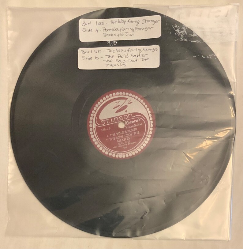 May include: A black vinyl record with a red and white label. The label has the text "Stinson Records" and the song titles "The Bold Soldier" and "The Sow Took the Measles" by Burl Ives.
