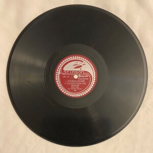 May include: A black vinyl record with a red label. The label has a white border and the text "Stinson Records Vocal-Guitar 345-1-B 1. THE BOLD SOLDIER 2. THE SOW TOOK THE MEASLES BURL IVES The Singing Cowboy"
