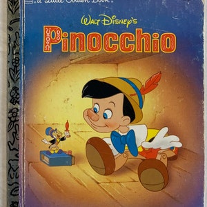 May include: A vintage Little Golden Book featuring Walt Disney's Pinocchio. The cover shows Pinocchio as a wooden puppet with a blue bow tie, a brown hat with a feather, and a mischievous grin. He is standing on a wooden floor with a small, yellow bird character in the background.