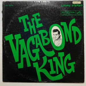 Pode incluir: Capa de álbum de vinil vintage para "The Vagabond King" de Mario Lanza. A capa é preta com letras verdes grandes. Um retrato de Mario Lanza está em uma moldura circular. O logotipo da RCA Victor e "Living Stereo" também são visíveis.