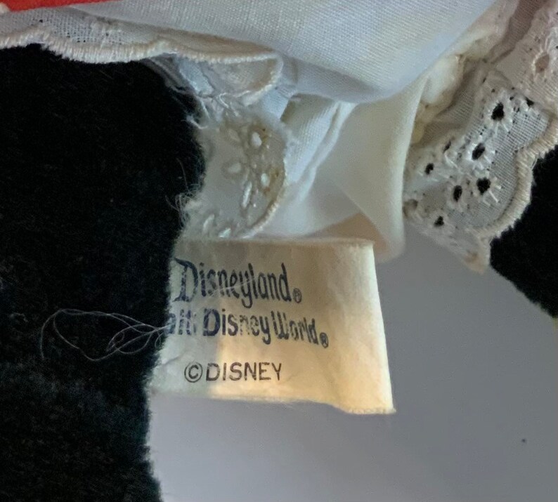 May include: Close-up of a white tag with black text that reads "Disneyland&reg; Walt Disney World&reg; &copy;DISNEY".