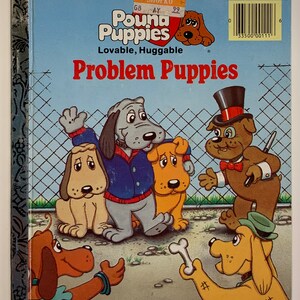 Puede incluir: Un libro "Little Golden Book" titulado "Pound Puppies Problem Puppies" con un grupo de cachorros de dibujos animados. La portada muestra un cachorro gris con un suéter azul, un cachorro amarillo, un cachorro marrón con un sombrero de copa y corbata de moño, y un cachorro amarillo con un sombrero verde. El libro forma parte de la serie "Lovable, Huggable".