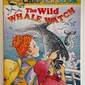 Op de afbeelding: Een boekomslagillustratie voor de "The Magic School Bus" hoofdstukboekenserie. De omslag toont een cartoonillustratie van een meisje met rood haar dat naar een walvisstaart wijst die uit het water springt. De titel van het boek is "The Wild Whale Watch" en het boeknummer is #3.