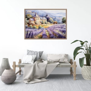 May include: A watercolor painting of a lavender field with a stone building in the background. The painting is framed in a light brown frame and is hanging on a white wall.