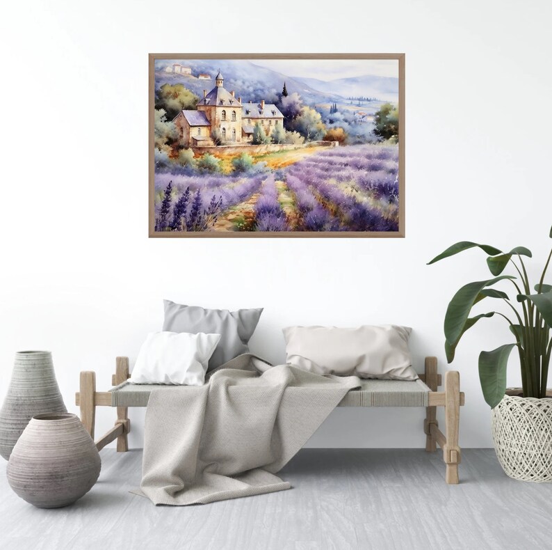 May include: A watercolor painting of a lavender field with a stone building in the background. The painting is framed in a light brown frame and is hanging on a white wall.