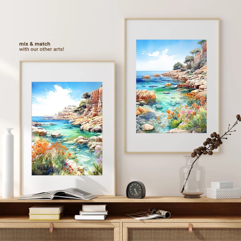 May include: Two framed watercolor paintings of a rocky coastline with turquoise water. The paintings are hanging on a white wall above a wooden shelf with books and a clock.