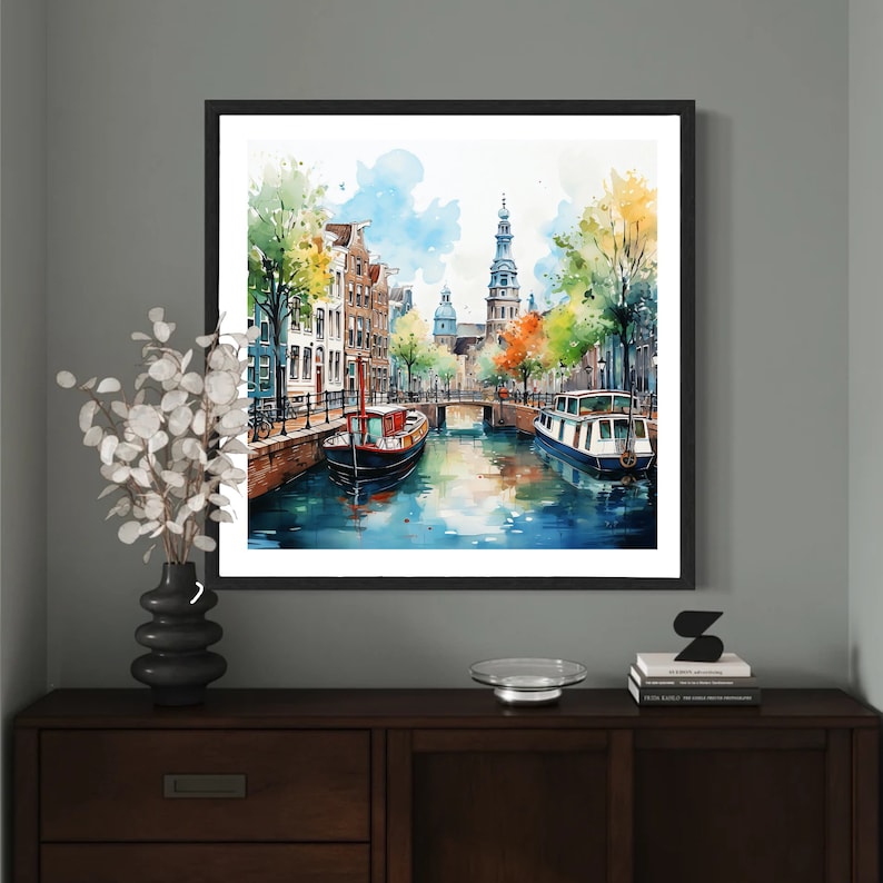 May include: Watercolor painting of a canal scene in Amsterdam, Netherlands. The painting features a narrow canal with buildings lining the sides, a bridge, and two boats. The buildings are painted in a variety of colors, including red, yellow, and blue. The boats are painted in a dark blue and red. The water is painted in a light blue color. The painting is framed in a black frame.