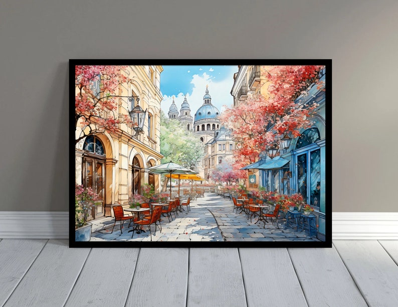 May include: A watercolor painting of a street scene in a European city. The street is lined with buildings and trees, and there are people sitting at tables outside a cafe. The buildings are painted in shades of yellow and brown, and the trees are green and red. The sky is blue and there are clouds in the sky.