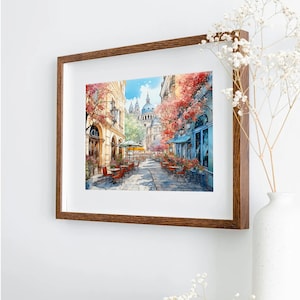 May include: A watercolor painting of a Parisian street scene with a cafe and a church in the background. The street is lined with trees and buildings, and there are people sitting at tables outside the cafe.