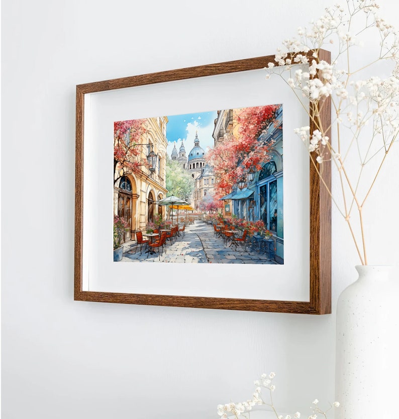 May include: A watercolor painting of a Parisian street scene with a cafe and a church in the background. The street is lined with trees and buildings, and there are people sitting at tables outside the cafe.