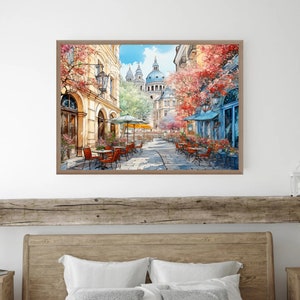 May include: A watercolor painting of a street scene in a European city. The street is lined with buildings, and there are trees and flowers in bloom. People are sitting at tables outside a cafe, enjoying the sunshine.