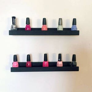 May include: Two black shelves with nail polish bottles in various colors, including pink, red, silver, and blue.