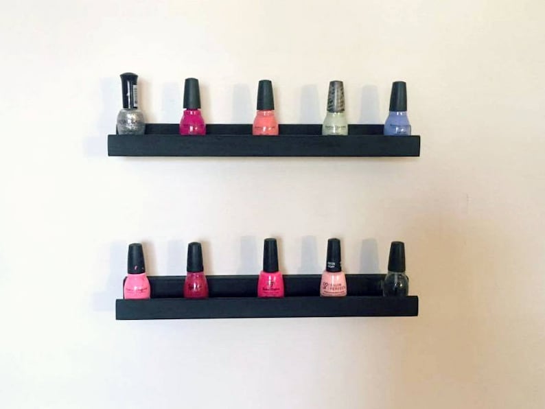May include: Two black shelves with nail polish bottles in various colors, including pink, red, silver, and blue.