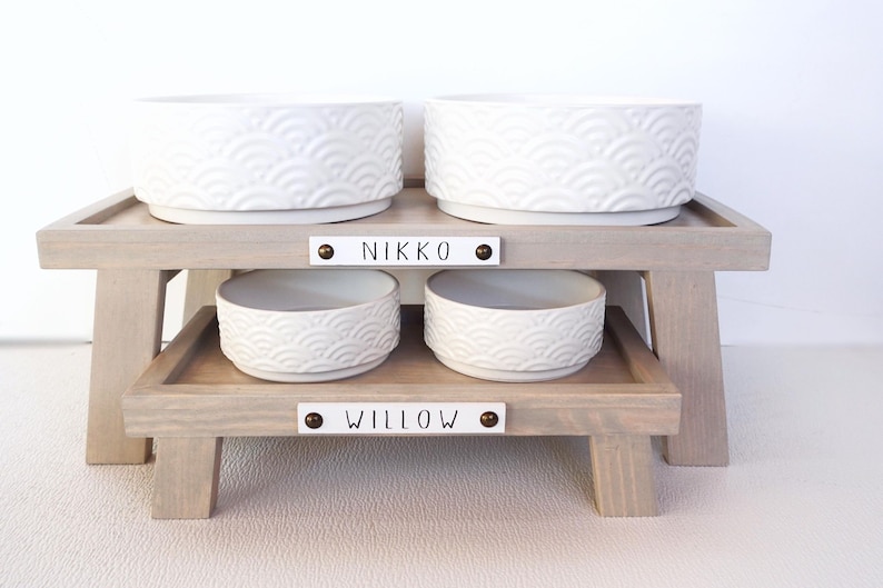 May include: Two raised dog food and water bowls with the names "Nikko" and "Willow" on the wooden stands.